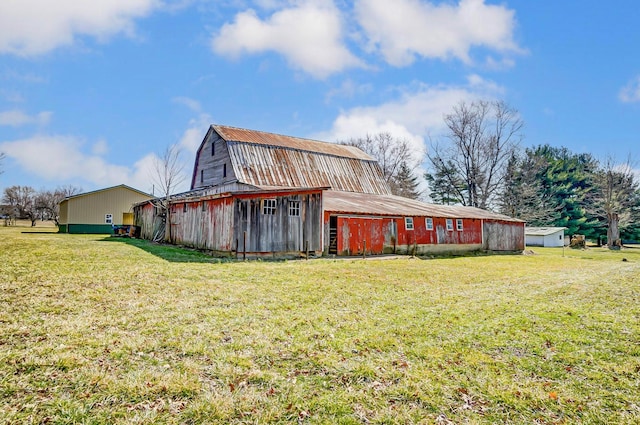 view of home's exterior with a yard, a gambrel roof, a barn, and an outdoor structure