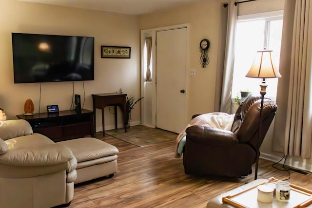 living area with a healthy amount of sunlight, baseboards, and wood finished floors