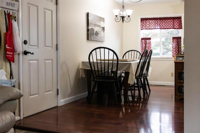 dining room featuring dark wood finished floors, visible vents, baseboards, and a chandelier