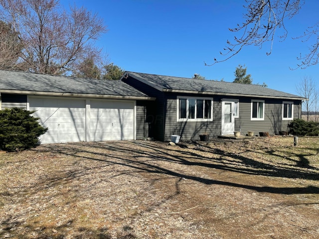 single story home with a garage, dirt driveway, and a shingled roof