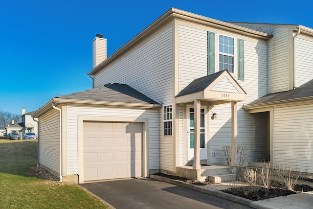 traditional-style house featuring aphalt driveway, an attached garage, and a chimney