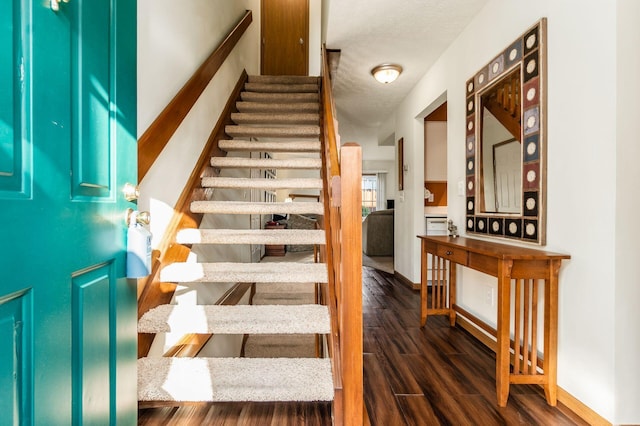 stairway with a textured ceiling and wood finished floors