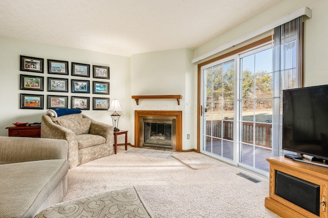 carpeted living room with a fireplace with flush hearth, baseboards, and visible vents