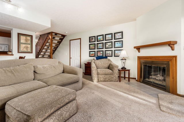 living area featuring stairway, carpet, baseboards, a fireplace with flush hearth, and tile patterned floors