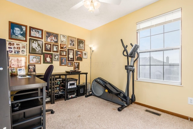 carpeted office space featuring ceiling fan, baseboards, visible vents, and a textured ceiling