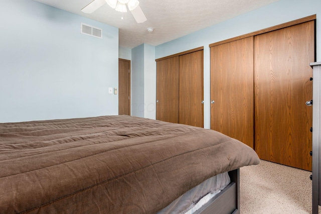 bedroom with visible vents, ceiling fan, a textured ceiling, and multiple closets