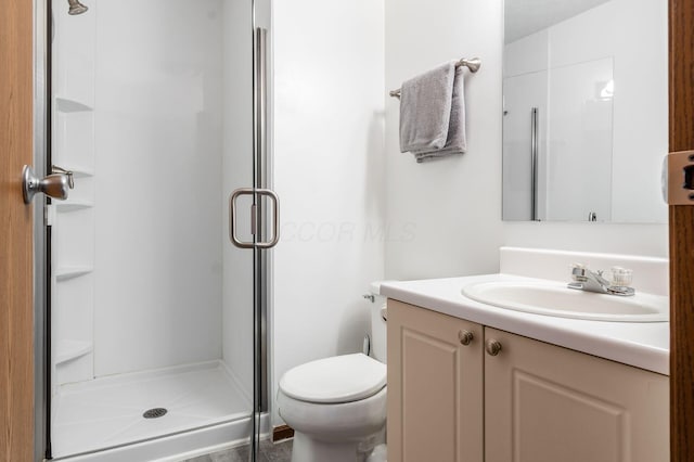 bathroom with vanity, a shower stall, and toilet