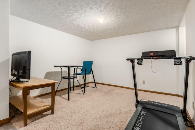 workout room featuring a textured ceiling and baseboards