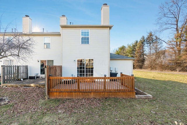 back of property featuring a deck, a chimney, and a yard