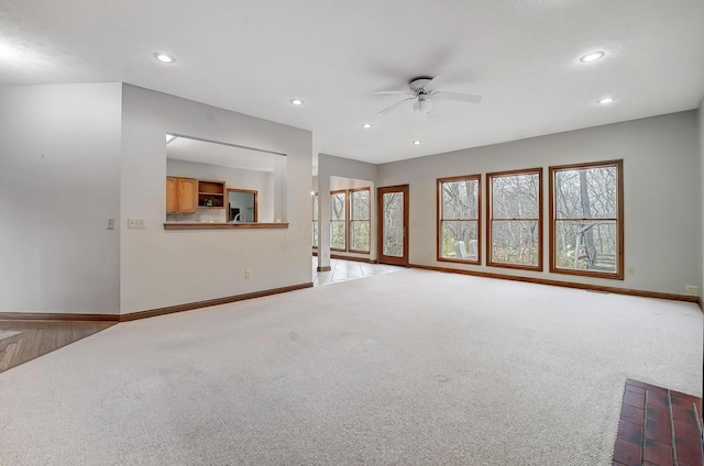 unfurnished living room featuring light colored carpet, baseboards, and a wealth of natural light