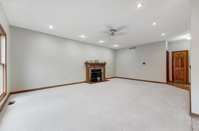 unfurnished living room with light colored carpet, visible vents, and a high end fireplace