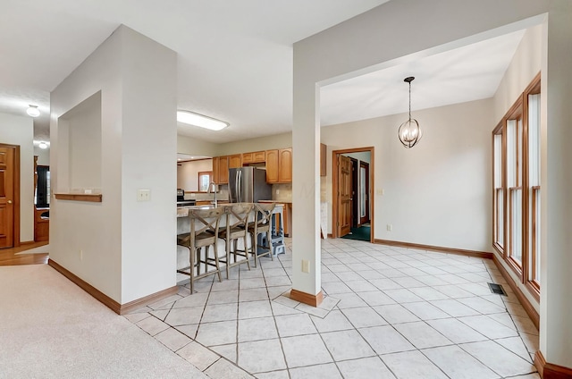 kitchen featuring a breakfast bar area, baseboards, freestanding refrigerator, and a sink