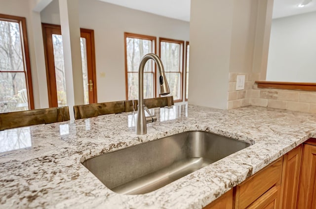 details with a sink, light stone countertops, and brown cabinets