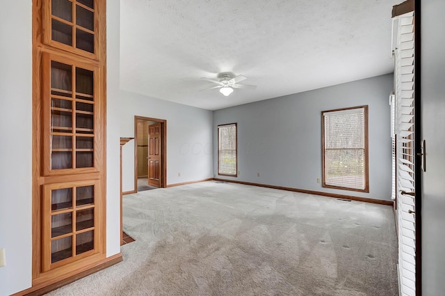 carpeted empty room with baseboards, a textured ceiling, and a ceiling fan