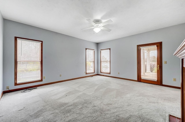 spare room featuring a wealth of natural light, light colored carpet, and baseboards