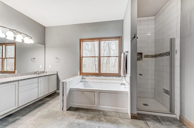 full bath featuring a bath, a stall shower, vanity, and baseboards