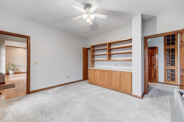 interior space with light carpet, a ceiling fan, and baseboards