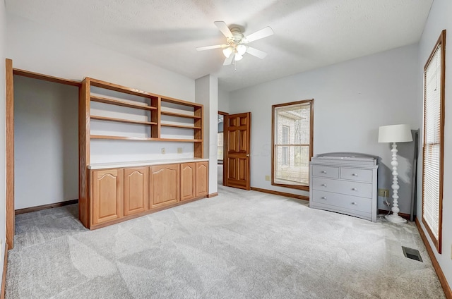 unfurnished office with light carpet, visible vents, a ceiling fan, and baseboards