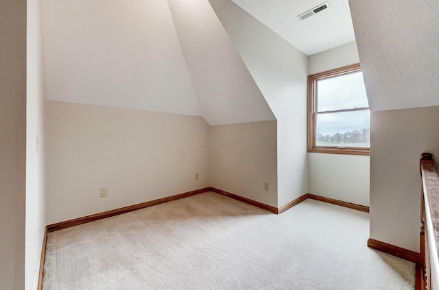 additional living space featuring visible vents, baseboards, carpet flooring, and vaulted ceiling