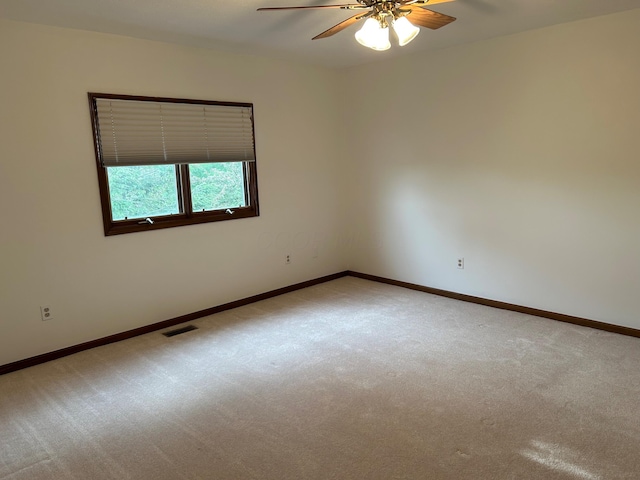 carpeted empty room featuring baseboards, a ceiling fan, and visible vents