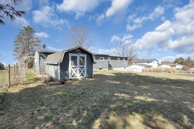 back of property featuring a yard, an outbuilding, a storage shed, and fence