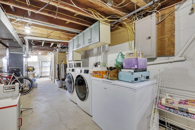 clothes washing area with electric panel, cabinet space, and washer and clothes dryer