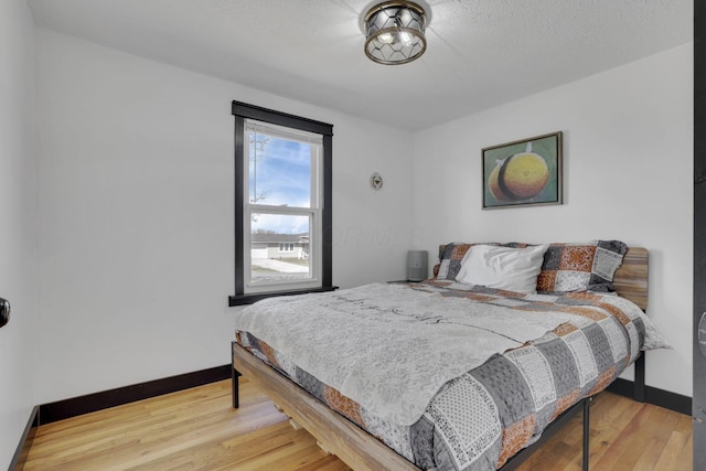 bedroom with wood finished floors, baseboards, and a textured ceiling