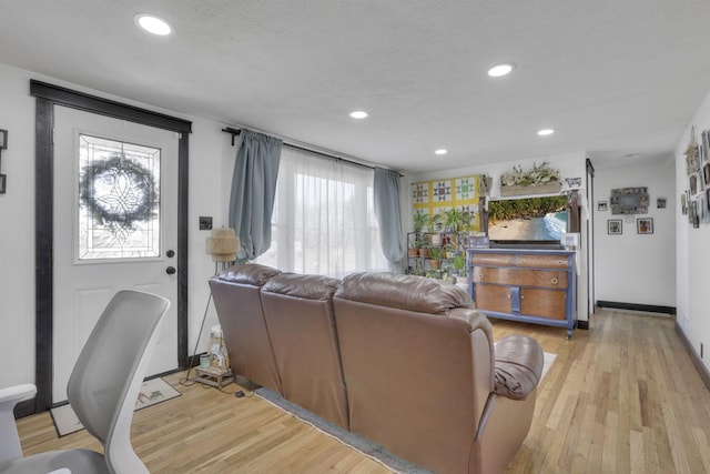 living area featuring recessed lighting, light wood-type flooring, baseboards, and a textured ceiling