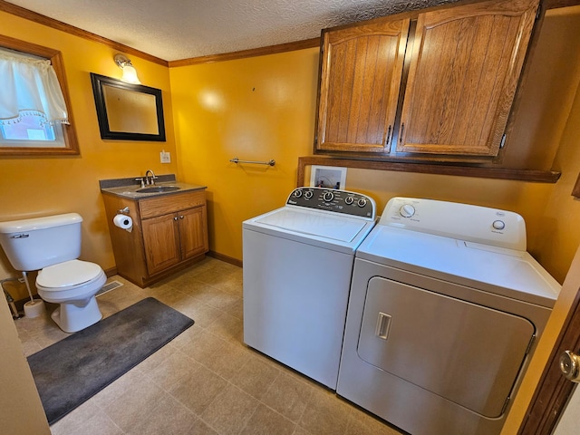 laundry area featuring laundry area, separate washer and dryer, ornamental molding, a sink, and a textured ceiling