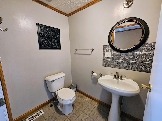 bathroom featuring visible vents, toilet, ornamental molding, a textured ceiling, and baseboards