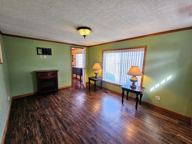 unfurnished room featuring a textured ceiling, crown molding, baseboards, and wood finished floors