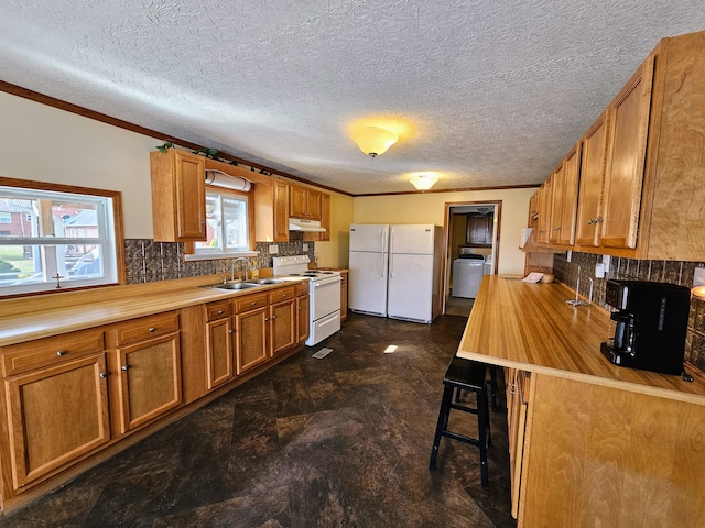 kitchen featuring a sink, white appliances, brown cabinets, and washer / clothes dryer