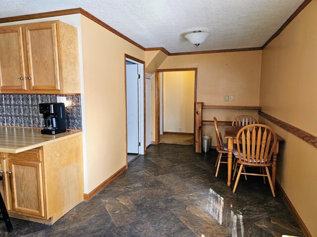 kitchen with tasteful backsplash, a textured ceiling, crown molding, and baseboards