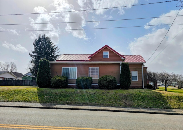 view of front of home with metal roof, a front yard, and fence