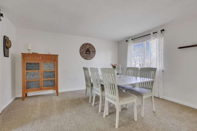 dining room featuring light colored carpet and baseboards