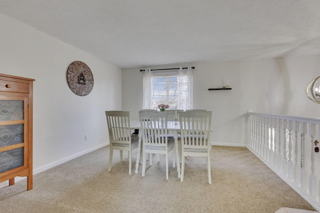 dining area featuring carpet flooring, baseboards, and a textured ceiling