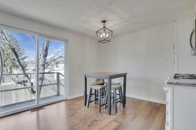 dining room with baseboards, wood finished floors, visible vents, and a textured ceiling