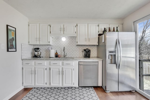 kitchen featuring dark wood-style floors, white cabinets, stainless steel appliances, and a sink