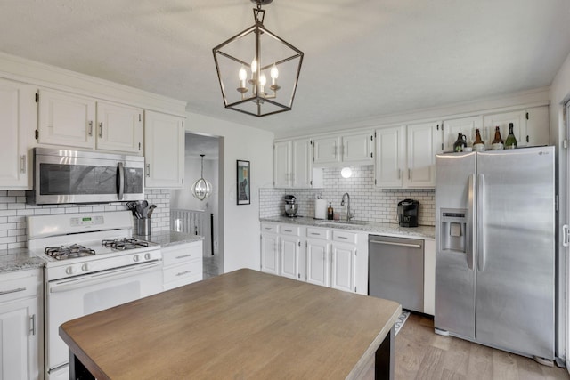 kitchen with light wood-type flooring, a sink, white cabinetry, appliances with stainless steel finishes, and decorative backsplash