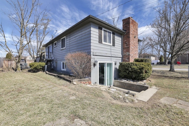 back of property with cooling unit, a lawn, a chimney, and fence