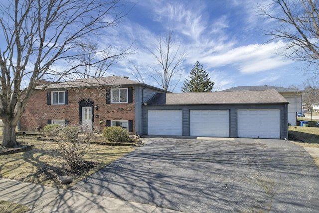 raised ranch with a garage, brick siding, and aphalt driveway