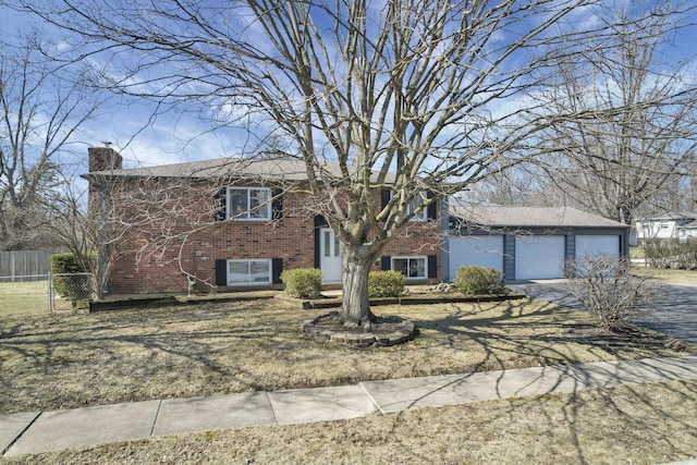 raised ranch with a garage, fence, brick siding, and a chimney