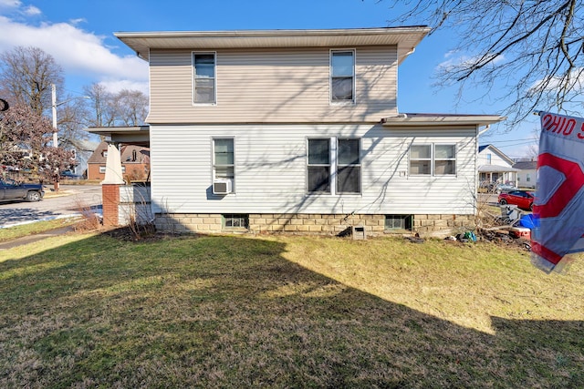 rear view of property featuring cooling unit and a lawn