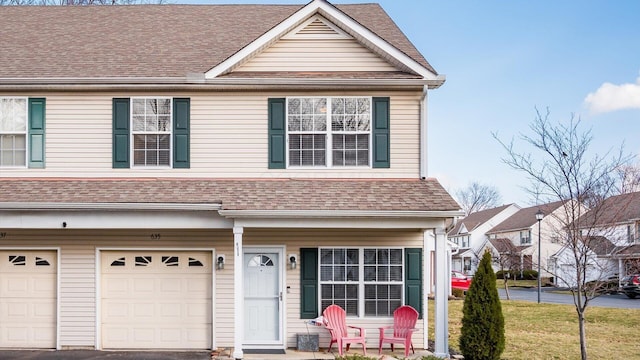 townhome / multi-family property with driveway, a front lawn, an attached garage, and a shingled roof