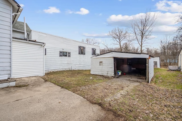 view of property exterior with a detached garage, an outdoor structure, and driveway