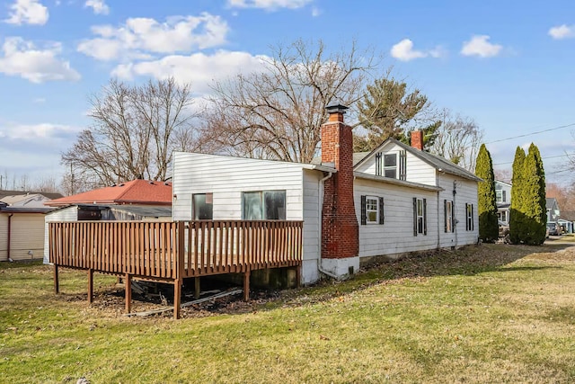 back of house with a wooden deck, a lawn, and a chimney