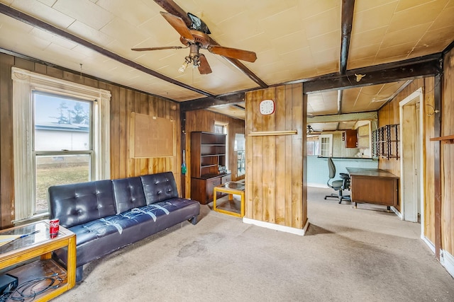 living area featuring wooden walls, carpet flooring, and ceiling fan