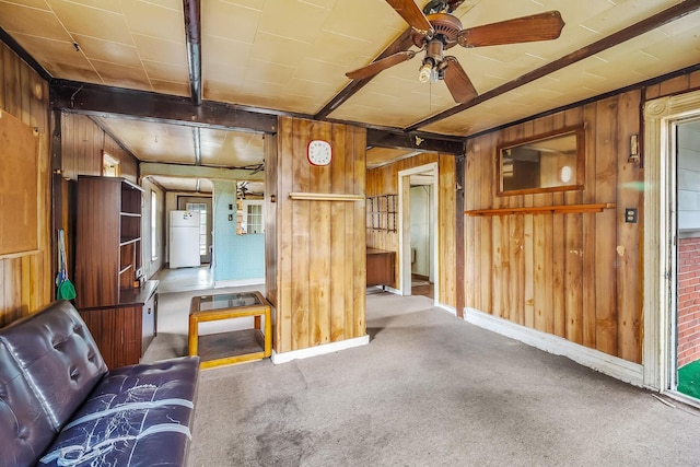 unfurnished living room featuring wooden walls, baseboards, carpet floors, and ceiling fan