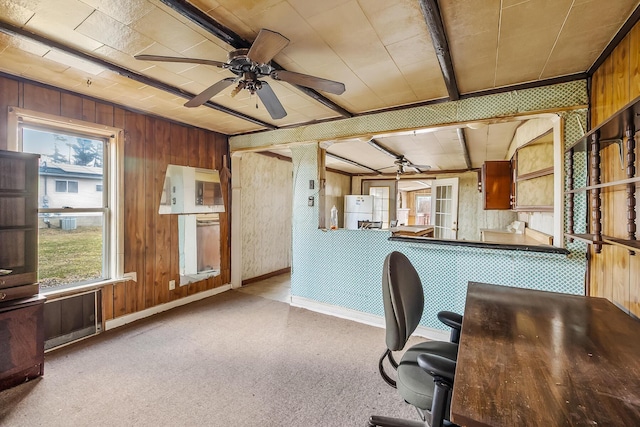 unfurnished office featuring wooden walls, baseboards, and ceiling fan