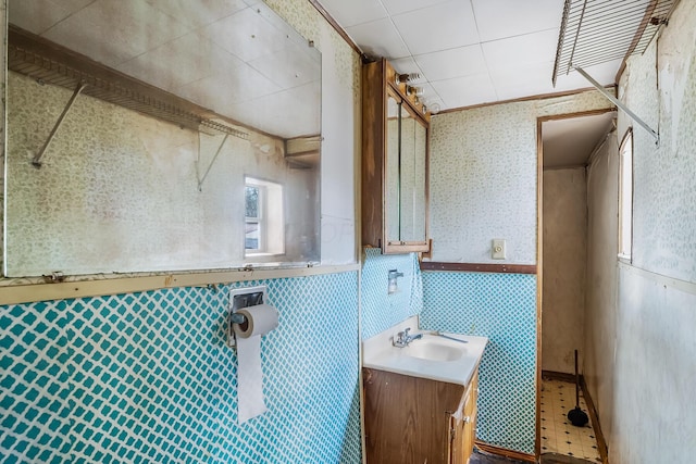 bathroom with wainscoting, wallpapered walls, and vanity